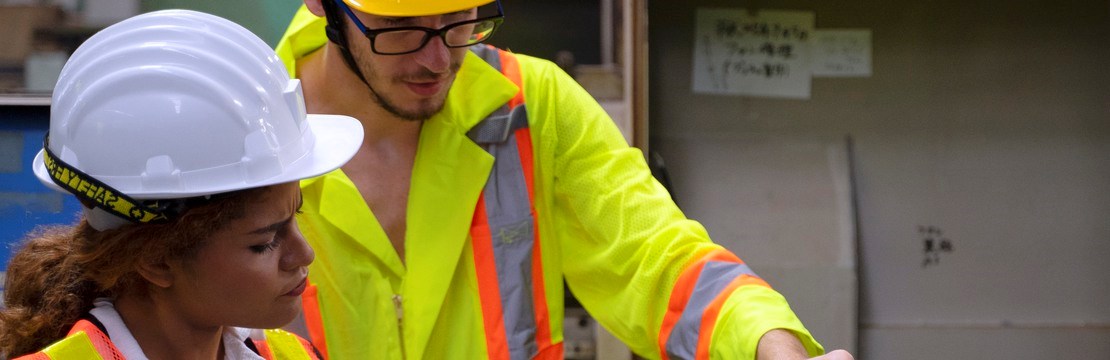 Kvinna och en man med dator i industrimiljö.